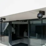 IP surveillance cameras mounted above the entrance of a modern commercial building