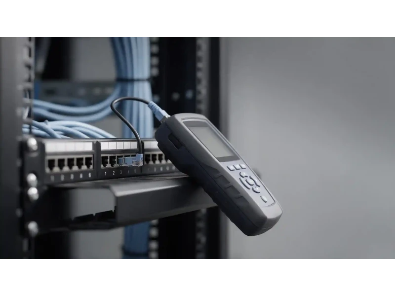 Cable certification testing — handheld field tester connected to a patch panel during commissioning