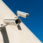 Outdoor IP cameras mounted on a building exterior under strong direct sunlight