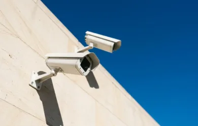 Outdoor IP cameras mounted on a building exterior under strong direct sunlight